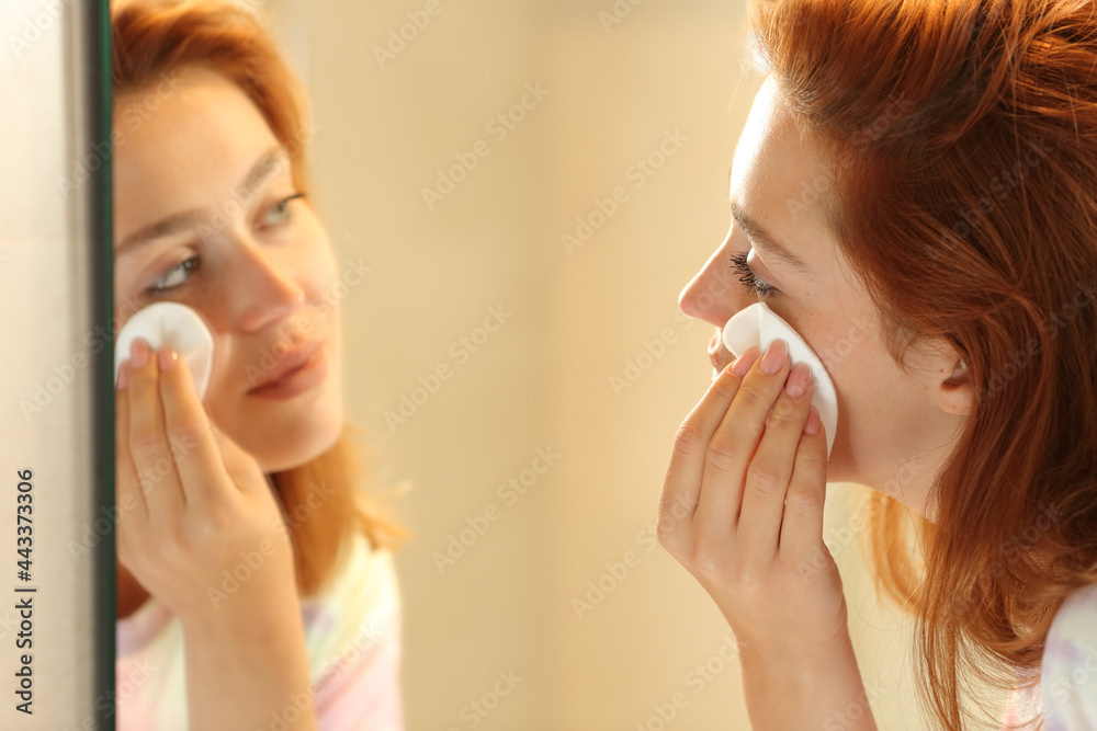 Wall mural Woman removing makeup with a tissue in the bathroom