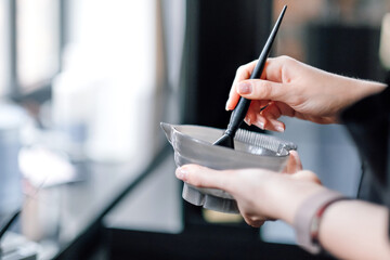 Hairdresser holding bowl with hair dye in beauty salon