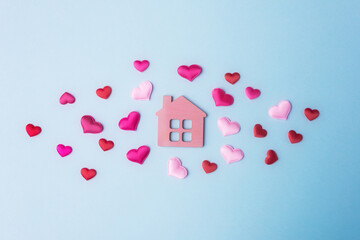 Pink toy house and decorative hearts on light blue background