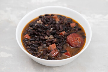 black beans with meat and sausages in white bowl