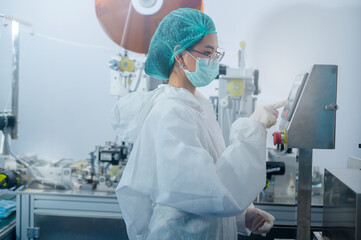 Workers producing surgical mask in modern factory, Covid-19 protection and medical concept.