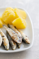 fried sardines with boiled potato on white dish