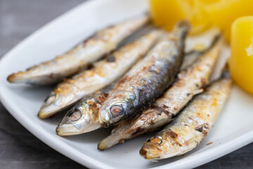 fried sardines with boiled potato on white dish