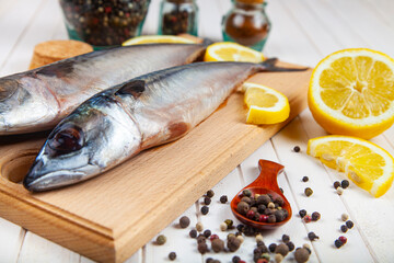 Raw mackerel on a cutting board with spices.
