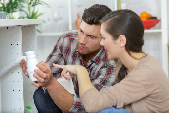 man and woman fitting the waste on a kitchen sink