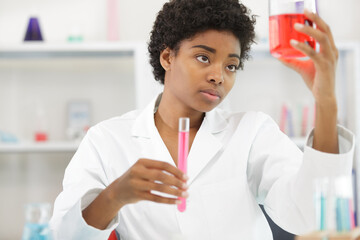 female scientist holding up a beaker to examine the liquid