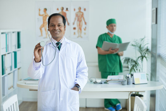 Cheerful experienced doctor holding stethoscope and looking at camera