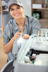 woman is using a screwdriver to fixing washing machine