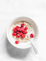 Oatmeal porridge with fresh raspberries on a light background, top view. Delicious breakfast