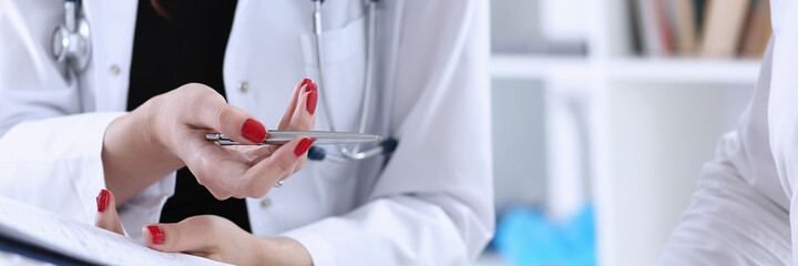 Female doctor hand hold silver pen and showing pad