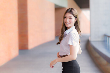 Portrait of an adult Thai student in university student uniform. Asian beautiful girl standing...