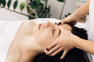 Obraz na płótnie Canvas Caucasian woman lying on spa bed get facial massage treatment with aroma essential oil skincare from massage therapist at beauty salon. Wellness body massage and face spa concept.
