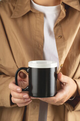Fototapeta na wymiar Black coffee mug mockup for design demonstration. Stylish cup mock up in female hands.