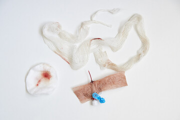 Used catheter, bandage and cotton pad with blood on white background