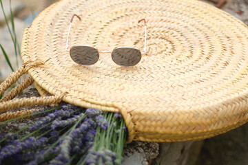 Fototapeta na wymiar Straw bag filled with fresh lavender flowers and retro sunglasses. Selective focus.