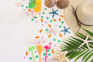 Fototapeta na wymiar nautical concept with palm leaf, beach hat, frui cocktail and starfish over white wooden background