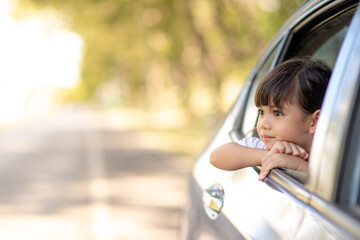Cute asian little child girl having fun to travel by car and looking out from ar window in cthe countryside