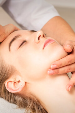 Young caucasian woman receiving a head and chin massage in a spa medical center