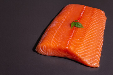 Fresh raw salmon or trout sea fish fillet on black stone background