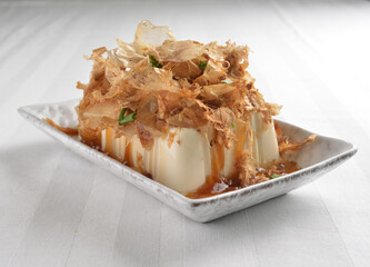steamed fresh tofu bean curd with Japanese dark soy sauce and bonito in white plate asian vegan halal menu