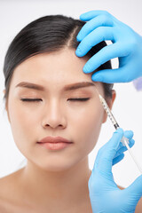 Pretty woman getting botox injections to lift her eyebrowns and look younger