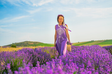 girl in a purple dress with a wreath and ribbons on her head in a lavender field at sunset. Boho style