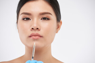 Portrait of serious attractive young woman getting lips injection at beauty salon