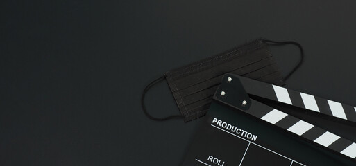 Black Clapper board or movie slate and black face mask on black blackground.