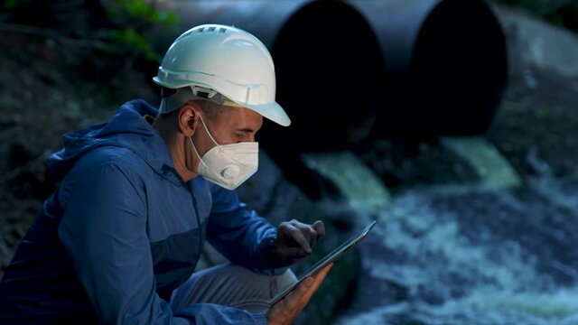 Environmental engineer. Wastewater pollution of environment and soil. Engineer with tablet checks waste water. Soil pollution. Preservation of environment. Ecologist with tablet checking waste water.