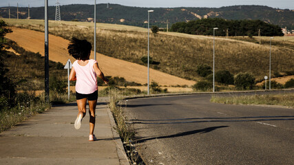 Hispanic woman running on a country road, shot from back