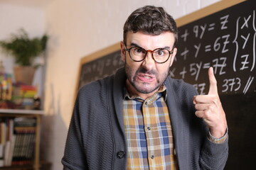 Angry teacher pointing with finger in classroom - obrazy, fototapety, plakaty