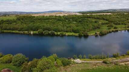 Drone image looking down onto a lake with green farmland surrounding. Taken in Lancashire England. 