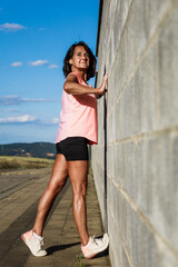 Fototapeta na wymiar Portrait of mature hispanic woman stretching muscles before running