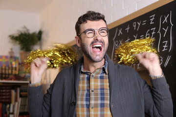 Fun teacher cheerleading with pom poms in classroom