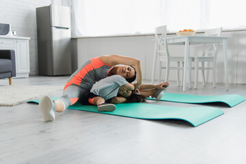 Asian mother and child stretching together on fitness mat