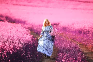 Wandaufkleber Mädchen in einem Feld lila Blumen in Lavendelfarben, violette und rosa Landschaft, glücklich und harmonisch © kichigin19