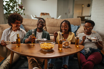 Group of friends eating takeout food and drinking beers