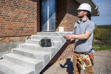 An electrician contractor examines a blueprint at a construction site.