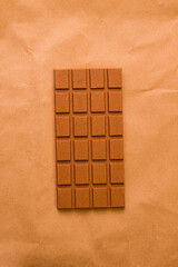 Milk chocolate on a brown background. View from above. Monochrome photo. Minimalism