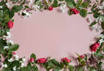 Fototapeta premium Floral frame of roses and other flowers on a pink background.