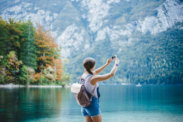 Sexy young girl takes pictures on a smartphone. White Caucasian girl on the background of turquoise water.