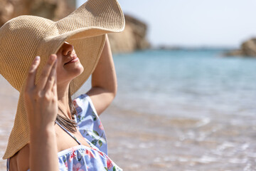 Portrait of a young woman in a big hat on the beach.