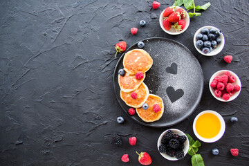 A healthy breakfast of cheese pancakes, berries, and honey. Creative atmospheric decoration