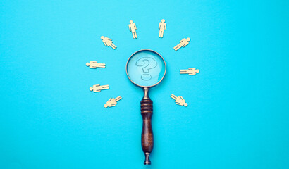 wooden men and vintage magnifying glass on a blue background Recruitment, search for talented...