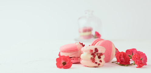 baked red strawberry macarons and rosebuds on a white table, gourmet almond flour dessert