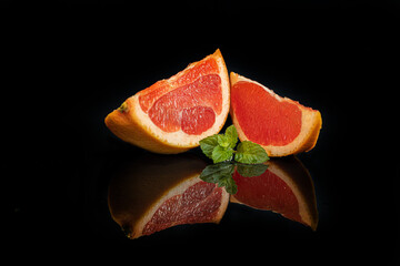 Slices of grapefruit on a dark background with a sprig of mint. Isolate.