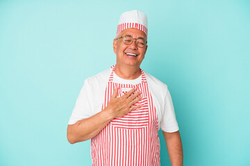 Senior american ice cream man woman holding isolated on blue background laughs out loudly keeping hand on chest.