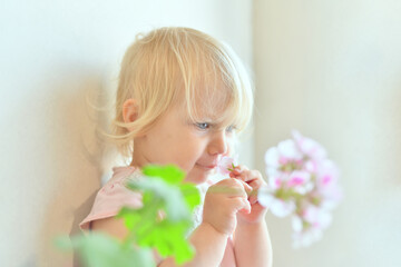 A little girl holds flowers in her hands and looks to the side.