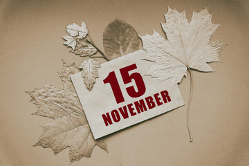 november 15. 15th day of month, calendar date.Envelope with the date and month, surrounded by autumn leaves on brown background.Autumn month, day of year concept