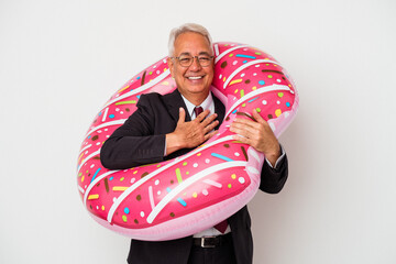 Senior american man holding inflatable donut isolated on white background laughs out loudly keeping hand on chest.
